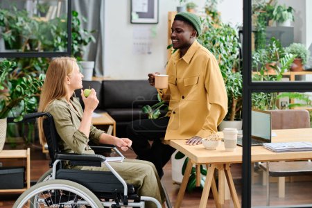 Foto de Dos jóvenes empleados interculturales discuten los puntos de trabajo durante el almuerzo mientras toman aperitivos y café o té en la oficina verde - Imagen libre de derechos