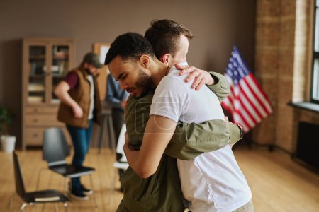 Photo for Young man giving hug to his friend with post traumatic syndrome during psychological session after discussing cases of bad life experience - Royalty Free Image