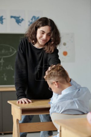 Photo for Pre-teen schoolboy touching hair of his classmate while making fun of him or just playing or kidding at break between lessons - Royalty Free Image