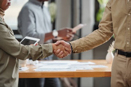 Photo for Close-up of handshake of two young intercultural business partners congratulating one another on signing new promising contract - Royalty Free Image