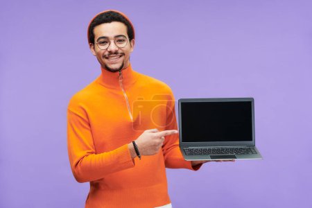 Photo for Young successful programmer pointing at blank screen of laptop while making presentation of new software and looking at camera - Royalty Free Image
