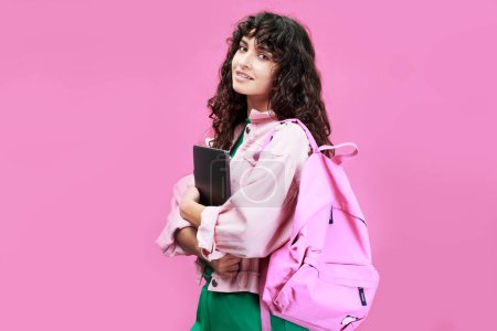 Téléchargez les photos : Étudiante intelligente du collège ou du lycée portant une veste en denim debout devant la caméra sur fond rose - en image libre de droit