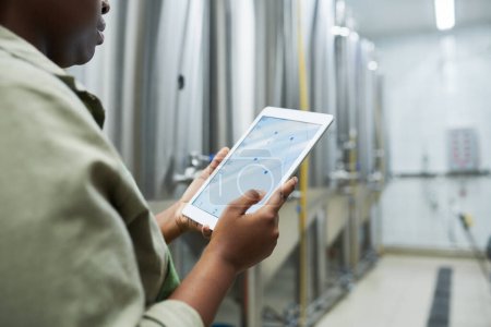Téléchargez les photos : Travailleur de brasserie vérifiant les graphiques en application sur tablette lors du contrôle de la production de bière - en image libre de droit