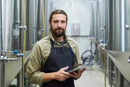 Téléchargez les photos : Ouvrier de brasserie de bière avec ordinateur tablette vérifiant chaque processus de production - en image libre de droit