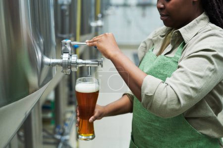 Photo for Cropped image of brewery worker filling big glass with beer from tank - Royalty Free Image