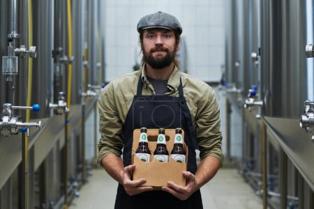 Téléchargez les photos : Portrait du propriétaire d'une brasserie positive tenant six paquets de bière - en image libre de droit