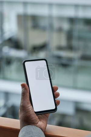 Photo for Hand of African American employee holding smartphone with blank screen where your advert or announcement can be placed - Royalty Free Image