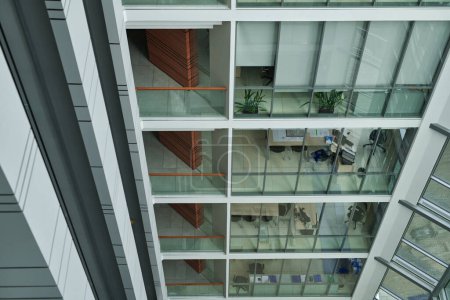 Photo for Above angle of interior of multi-storey business center with openspace offices for employees of various companies behind large windows - Royalty Free Image