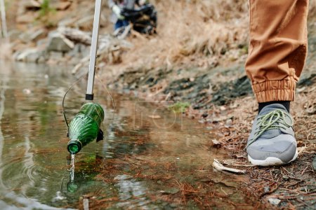 Foto de Voluntario recogiendo botellas de vidrio al limpiar el lago del bosque - Imagen libre de derechos