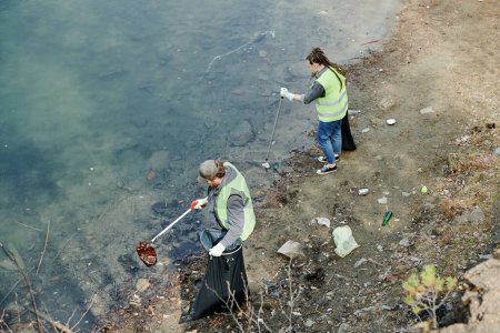 Foto de Jóvenes recogiendo basura en la orilla del lago, vista desde arriba - Imagen libre de derechos