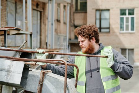 Téléchargez les photos : Homme travaillant au chantier de démolition, triant les tiges métalliques - en image libre de droit