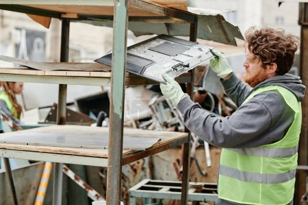 Photo for Volunteer putting metal pieces on shelves at scrapyard, preparing for recycling - Royalty Free Image