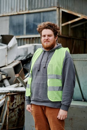 Photo for Portrait of volunteer standing at pile of scrap metal and looking at camera - Royalty Free Image