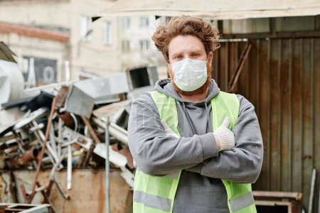 Photo for Confident volunteer in medical mask crossing arms and looking at camera after sorting scrap metal - Royalty Free Image