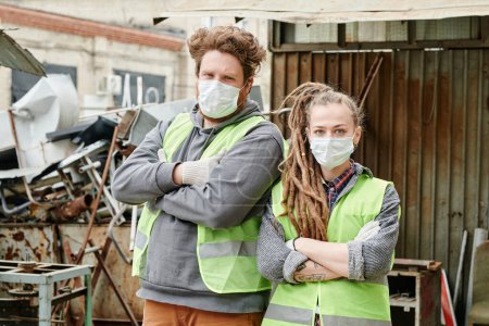 Team von Freiwilligen in Schutzmasken und Neon-Westen bereit, Altmetall zu sortieren