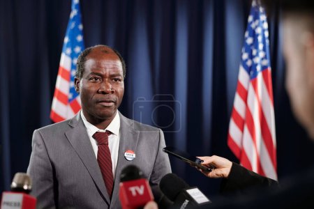 Photo for African American male delegate in formalwear giving interview to journalists after political event in conference hall - Royalty Free Image