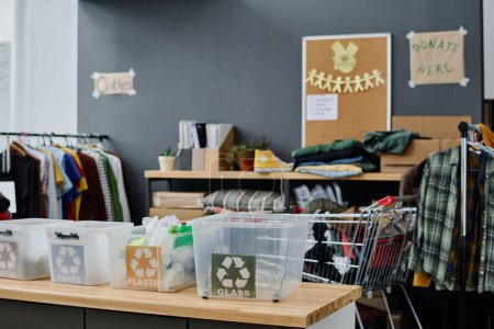 Photo for Part of spacious storage room or office of volunteering organization with plastic boxes for different types of garbage and second hand clothes - Royalty Free Image