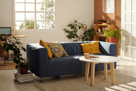 Foto de Moderno salón con cómodo sofá y mesa de centro de pie en la alfombra - Imagen libre de derechos