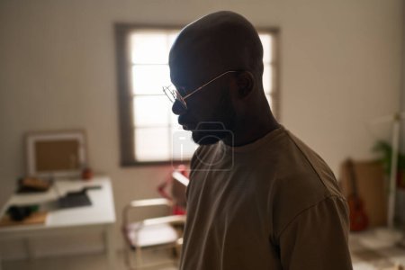 Téléchargez les photos : Jeune homme afro-américain dans la mélancolie rester seul dans la chambre - en image libre de droit