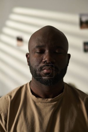 Foto de Imagen vertical del hombre afroamericano con los ojos cerrados concentrando su atención - Imagen libre de derechos