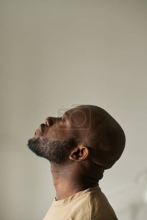 Téléchargez les photos : Image verticale de l'homme afro-américain méditant les yeux fermés sur fond gris - en image libre de droit