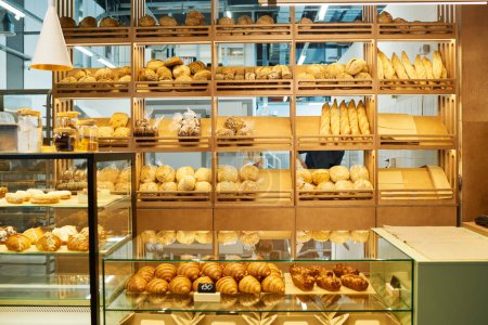 Téléchargez les photos : Comptoir de boulangerie et présentoirs avec assortiment de pains et pâtisseries frais vendus à la cafétéria après cuisson par un boulanger professionnel - en image libre de droit