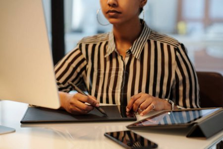 Téléchargez les photos : Mains de la jeune graphiste féminine avec stylet et pavé tactile assis par bureau devant le moniteur d'ordinateur et la création de nouveaux croquis - en image libre de droit