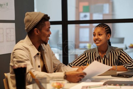 Foto de Joven mujer de negocios sonriente mirando a un colega masculino durante la discusión de los puntos de trabajo y la toma de decisiones sobre tareas y objetivos clave - Imagen libre de derechos