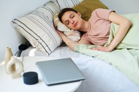 Téléchargez les photos : Jeune femme reposant sur le lit dans sa chambre après avoir utilisé des gadgets - en image libre de droit