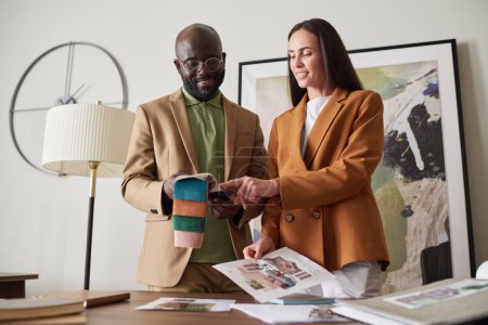 Foto de Dos jóvenes diseñadores creativos eligen el color y el textil de la colección de muestras mientras trabajan sobre el diseño de un nuevo interior en la reunión - Imagen libre de derechos