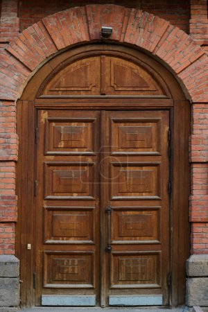 Photo for Closed wooden door on front part of red brick historical institution which represents place of interest for tourists of modern city - Royalty Free Image