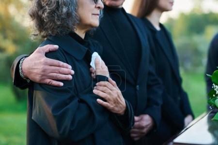 Photo for Hand of mature man on shoulder of his wife or sister with handkerchief lamenting passes away relative or family member during funeral service - Royalty Free Image