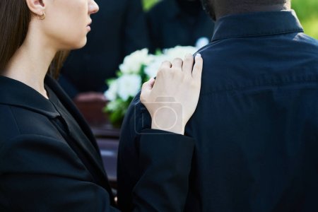 Téléchargez les photos : Gros plan de la jeune femme de soutien consolant son ami en deuil portant des vêtements de deuil lors des funérailles de sa femme ou d'un autre membre de sa famille - en image libre de droit