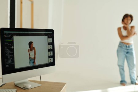 Photo for Focus on computer screen with shot of young African American female fashion model posing for camera during photo session in isolation - Royalty Free Image