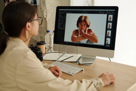 Téléchargez les photos : Focus sur l'écran de l'ordinateur avec des photos de jeunes mannequins féminins assis dans l'isolement et regardant la caméra pendant la séance photo - en image libre de droit