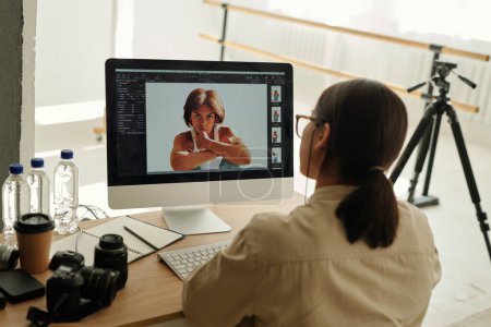 Téléchargez les photos : Ordinateur avec des photos de mannequin afro-américaine regardant la caméra pendant la séance photo tout en posant en isolement en studio - en image libre de droit
