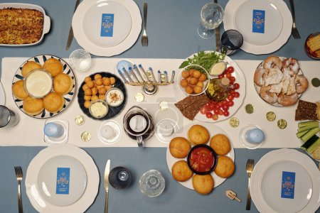 Photo for Top view of served dinner table with homemade food and drinks prepared for guests and family members for Hanukkah celebration - Royalty Free Image