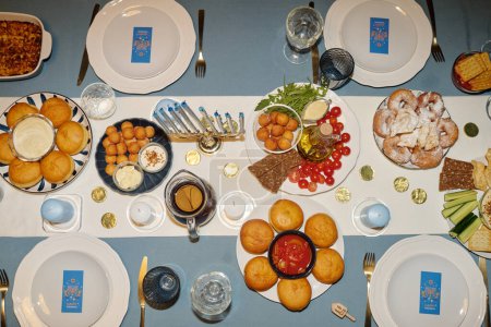 Téléchargez les photos : Vue d'en haut de la table de fête servie avec de la nourriture et des boissons faites maison pour les invités invités par la famille juive pour le dîner Hanoukka - en image libre de droit
