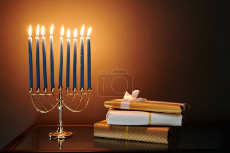 Téléchargez les photos : Empilement de boîtes-cadeaux emballées et menorah avec neuf bougies allumées préparées pour la célébration de Hanoukka debout devant la caméra - en image libre de droit