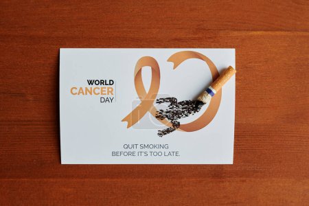 Photo for Shot of handmade postcard with lung cancer ribbon, cigarette butts and slogan proclaiming to quit smoking before it is too late - Royalty Free Image