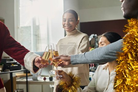 Photo for Hands of young intercultural office workers clinking with flutes of sparkling champagne while toasting for good luck in new business projects - Royalty Free Image