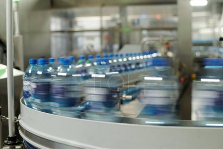 Partie de la chaîne de production mobile avec des bouteilles en plastique bouchées contenant de l'eau minérale ou une autre boisson dans une grande usine moderne