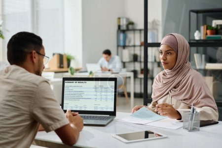 Téléchargez les photos : Deux jeunes entrepreneurs musulmans interculturels se regardent lors d'une rencontre sur le lieu de travail lors de la discussion des points de travail - en image libre de droit