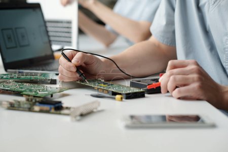 Photo for Hands of young worker of troubleshooting service center using electric handtool while checking and repairing computer motherboard - Royalty Free Image