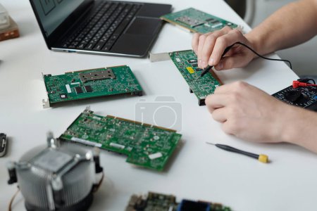 Photo for Hands of unrecognizable male technician of troubleshooting service center repairing computer motherboard with transmission tweezers - Royalty Free Image