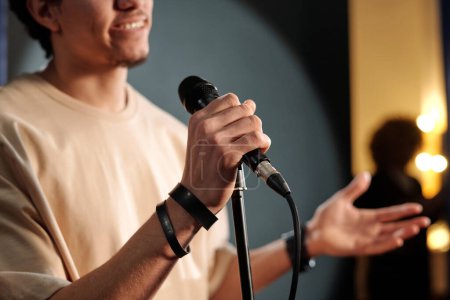 Photo for Hand of young male comedian of stand up club with microphone standing in front of camera during performance and pronouncing monologue - Royalty Free Image