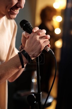 Téléchargez les photos : Mains de l'acteur ou du présentateur masculin avec microphone prononçant le monologue ou parlant au public pendant la représentation sur scène - en image libre de droit