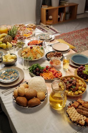 Téléchargez les photos : Vue verticale en angle élevé tourné pas de personnes plan de table de fête avec divers plats délicieux sur elle préparée pour la célébration de l'Aïd Al-Fitr - en image libre de droit