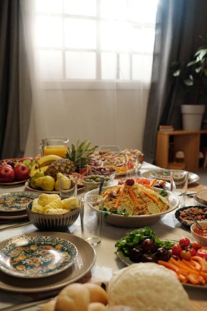 Vertical no people shot of abundant festive table served with homemade dishes, vegetables and fruits for Eid Al-Fitr celebration, copy space