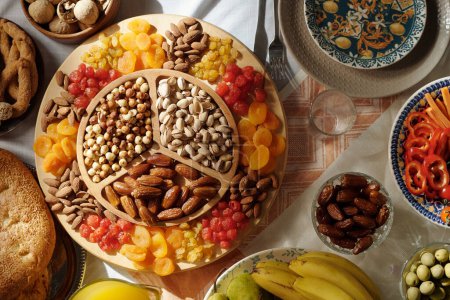 No people flat lay shot of sweet dried fruit and nits on platter on festive table served for Islamic holiday celebration